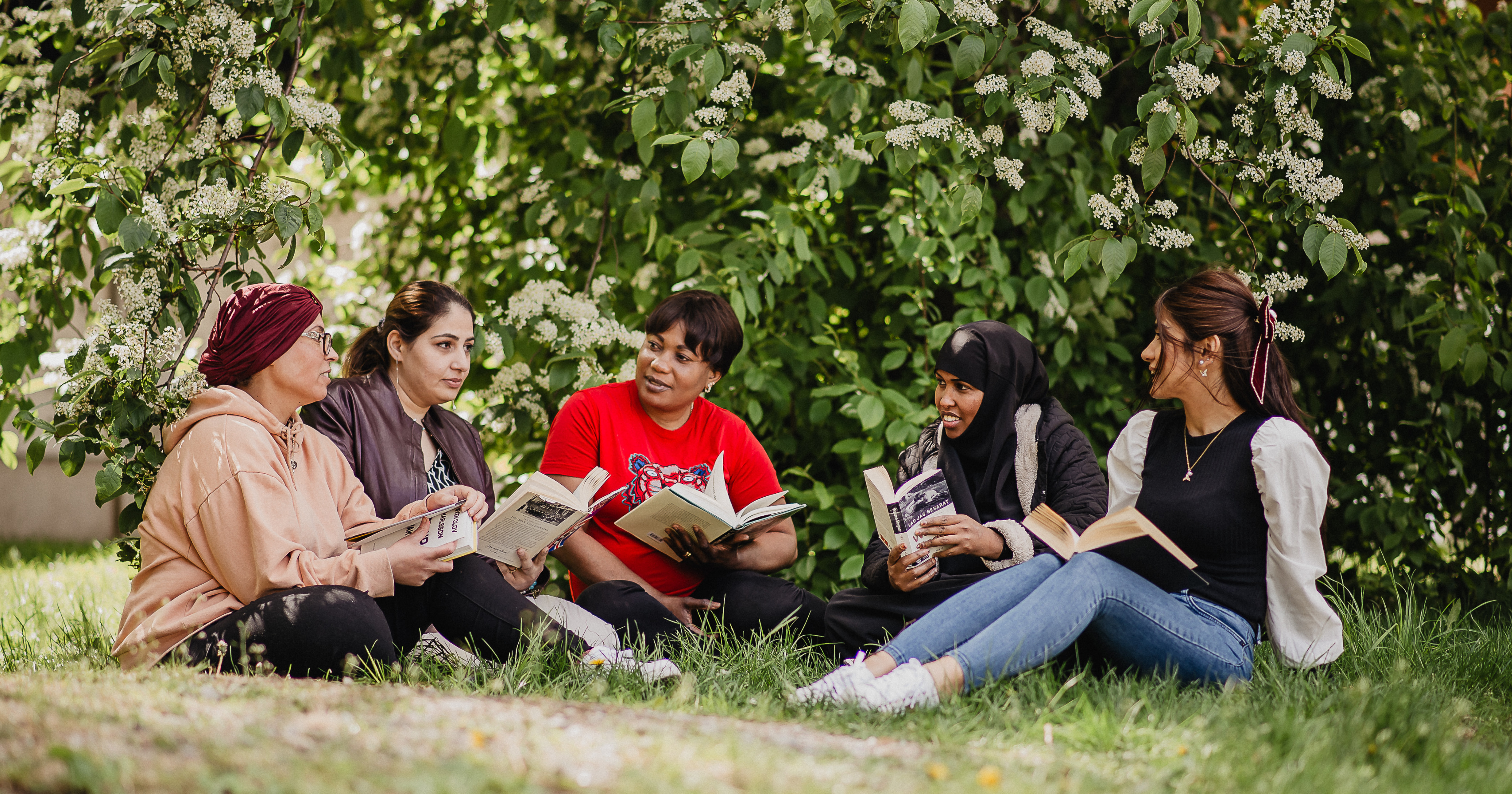 En grupp tjejer läser i gräset