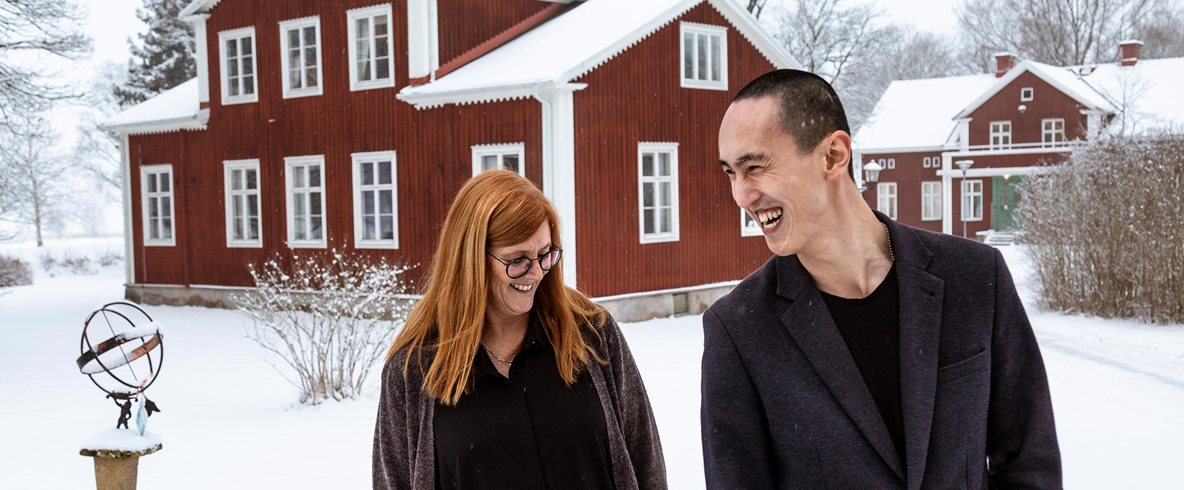 Lisa och Andreas fotograferade på Kävestas område. Marken och taken på de röda husen är täckta av snö.