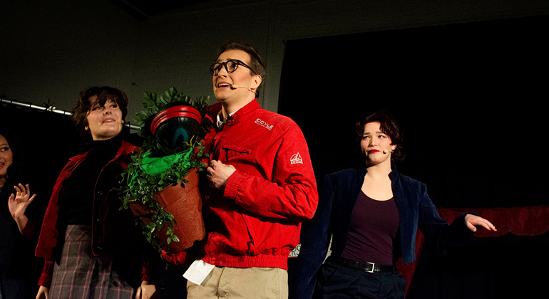 En ung person i r&ouml;d jacka upptr&auml;der p&aring; en teaterscen.