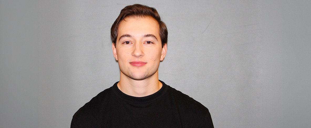 En ung person ler och kollar in i kameran.