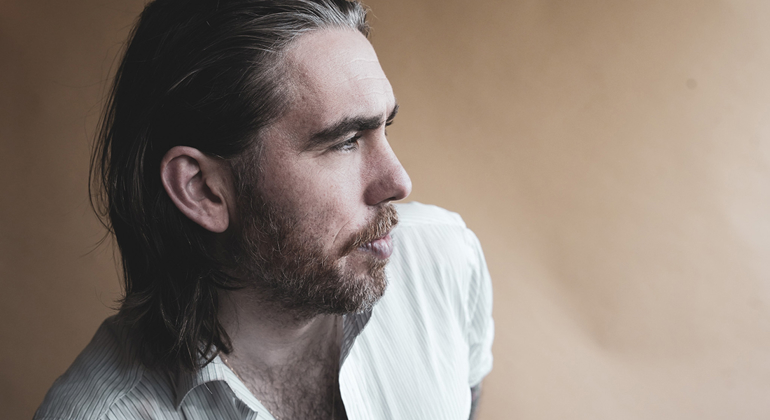 Valter Nilsson. En person i vit randig skjorta sitter i profil inomhus.