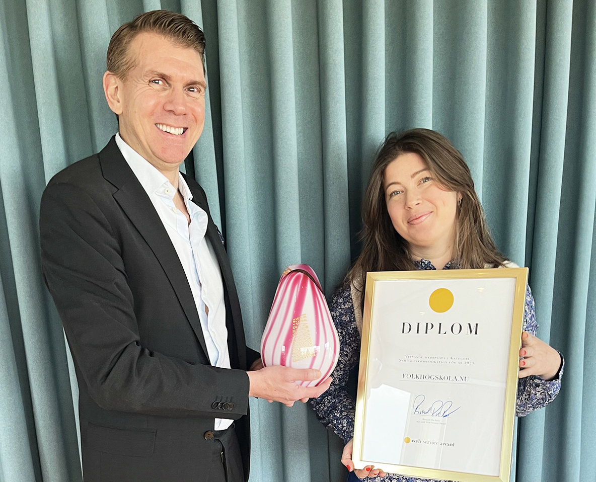 En leende man överlämnar en glasskulptur till en leende kvinna.