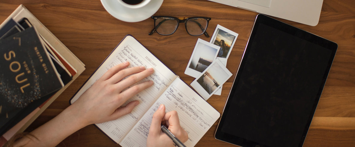 Bild. En hand med en penna som skriver i en kalender.