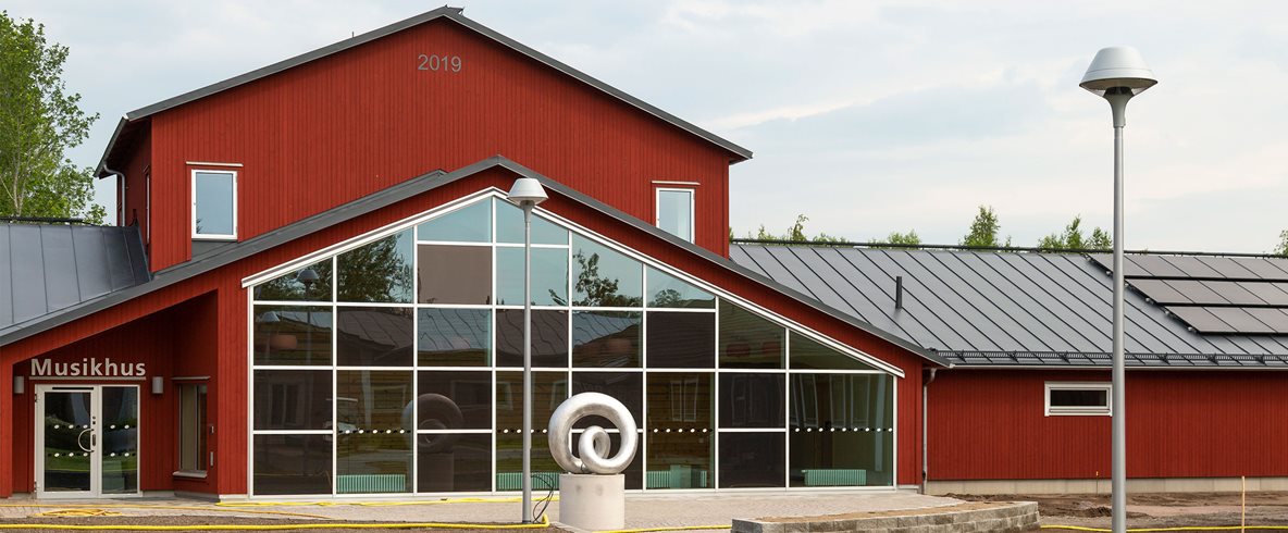 Det nya musikhuset på Kävesta, en röd byggnad med stor glasfasad.