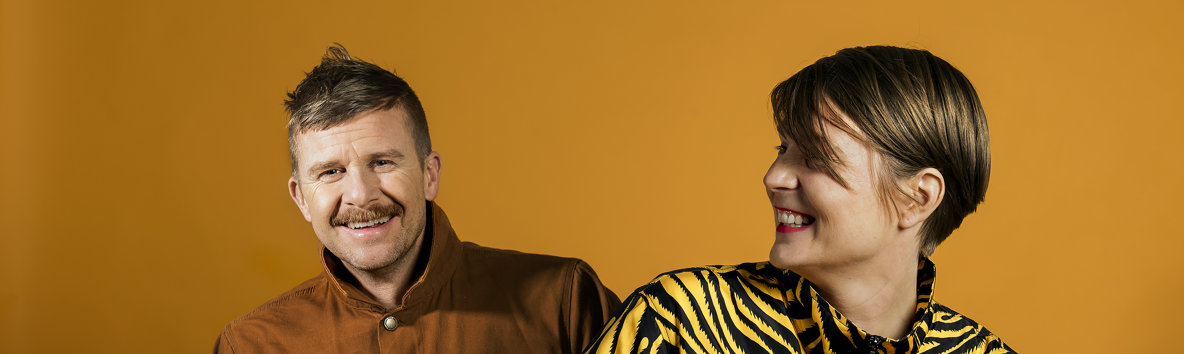 Linus Torgeby och Åsa Ekman framför en orange bakgrund.