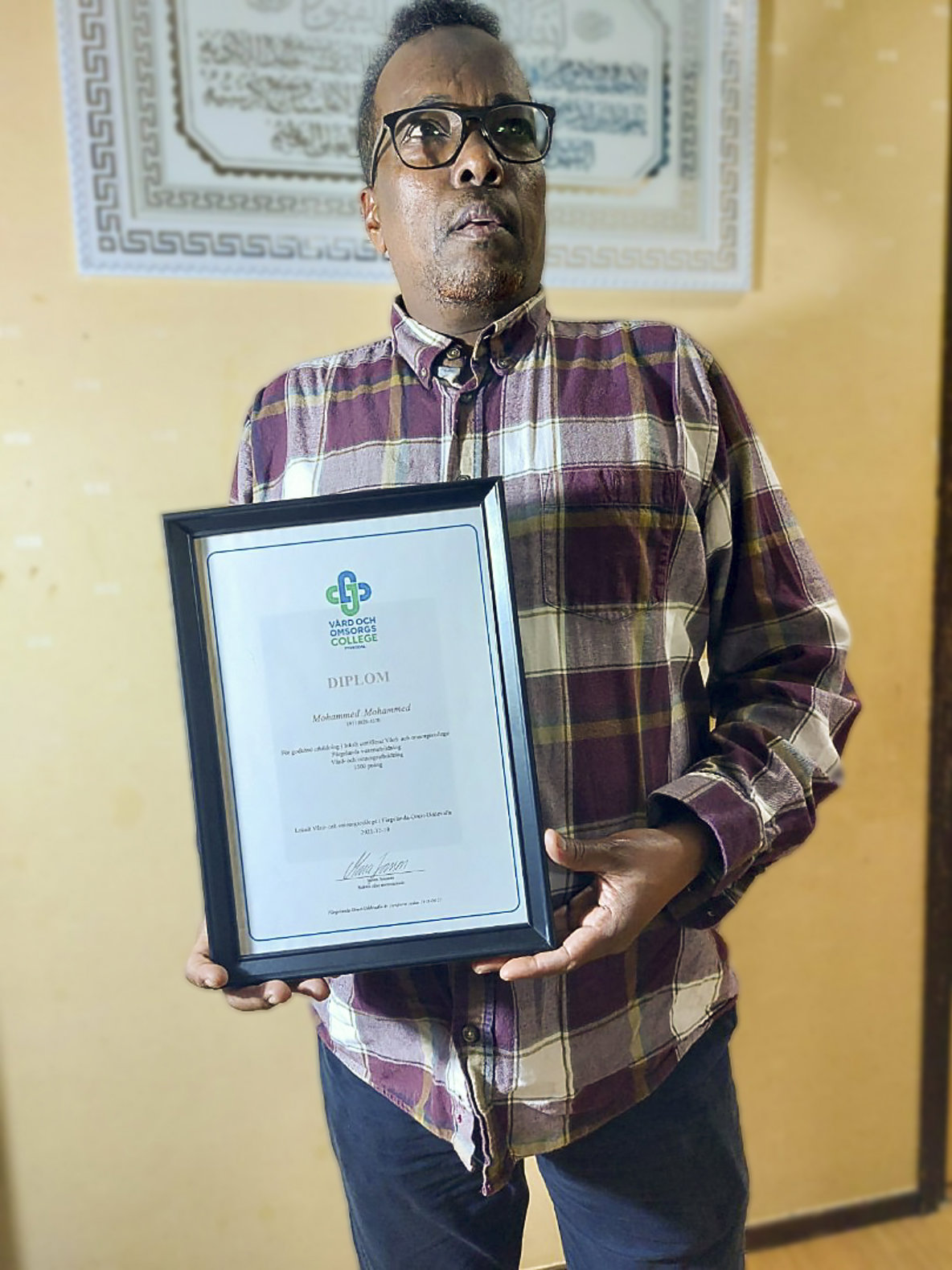 Mohammed Mahamud visar upp sitt undersköterskediplom.