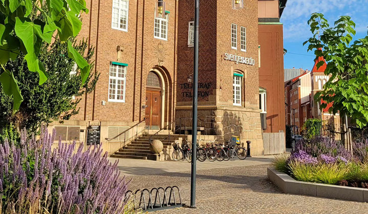 Brun tegelbyggnad med litet torg framför.