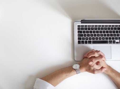 Bild: Knäppta händer på ett tangentbord, sett ovanifrån.